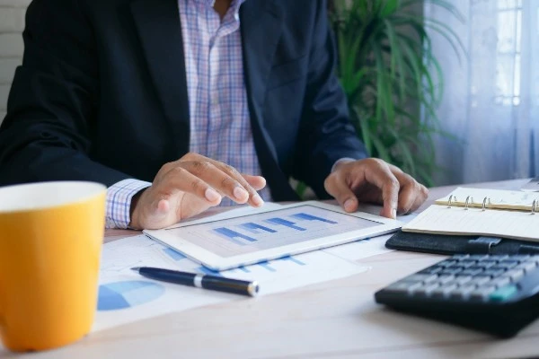 A business executive analyzing financial growth charts on a digital tablet during a Creditors Voluntary Liquidation review in Singapore.