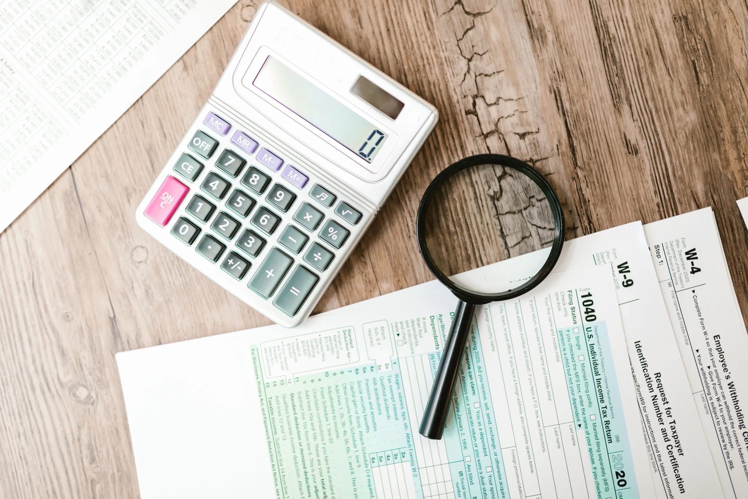 Tax documents, a calculator, and a magnifying glass illustrating an audit of GST liabilities and tax risks in Singapore.