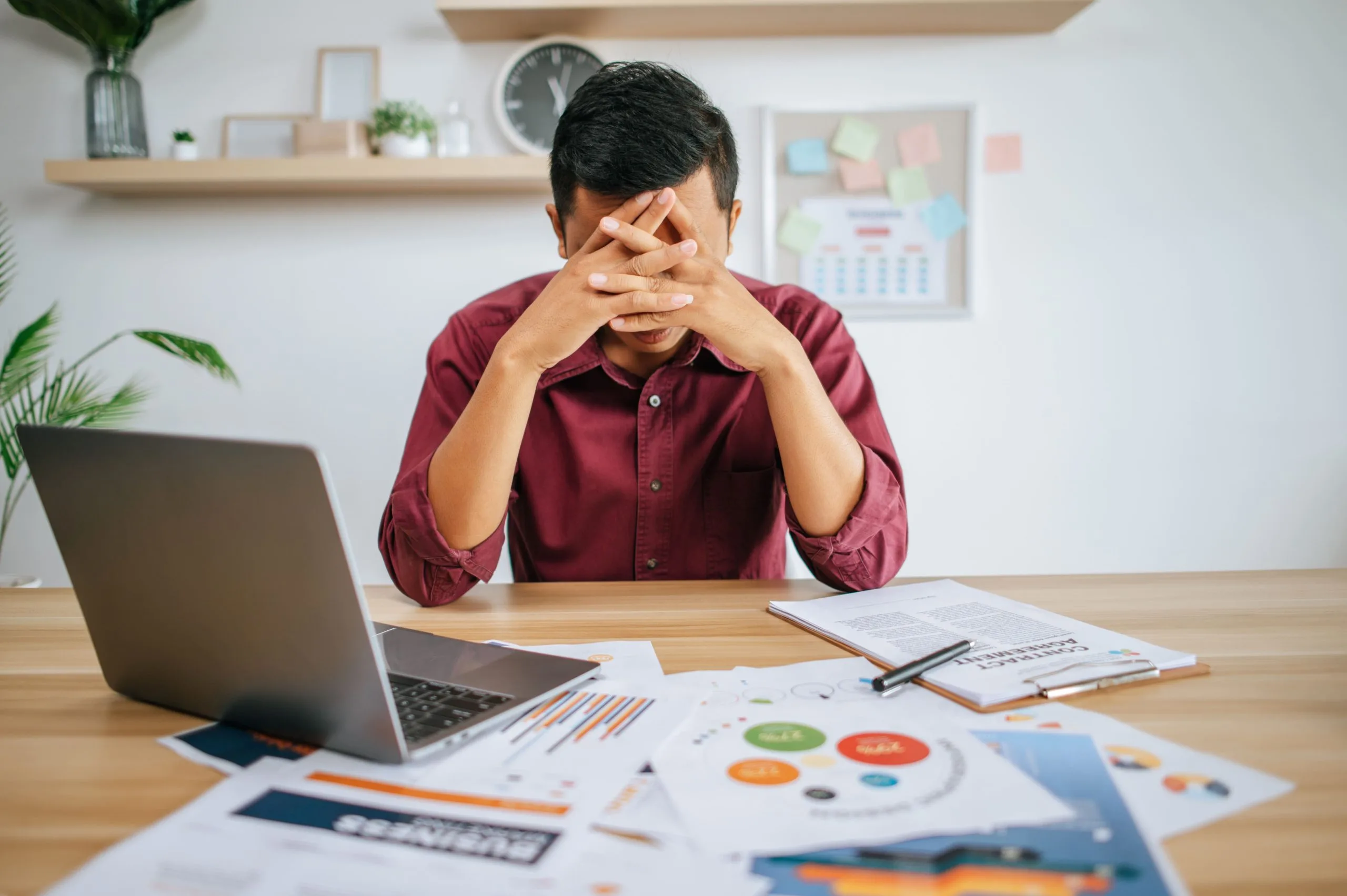 Man working with laptop and paperwork with stress