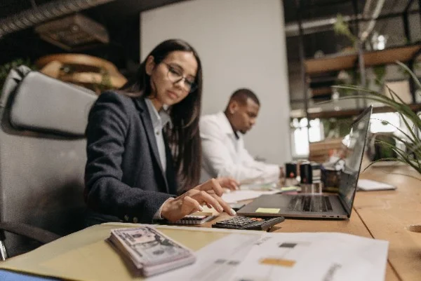 Business professional using a calculator and reviewing cash reserves to assess company liquidity