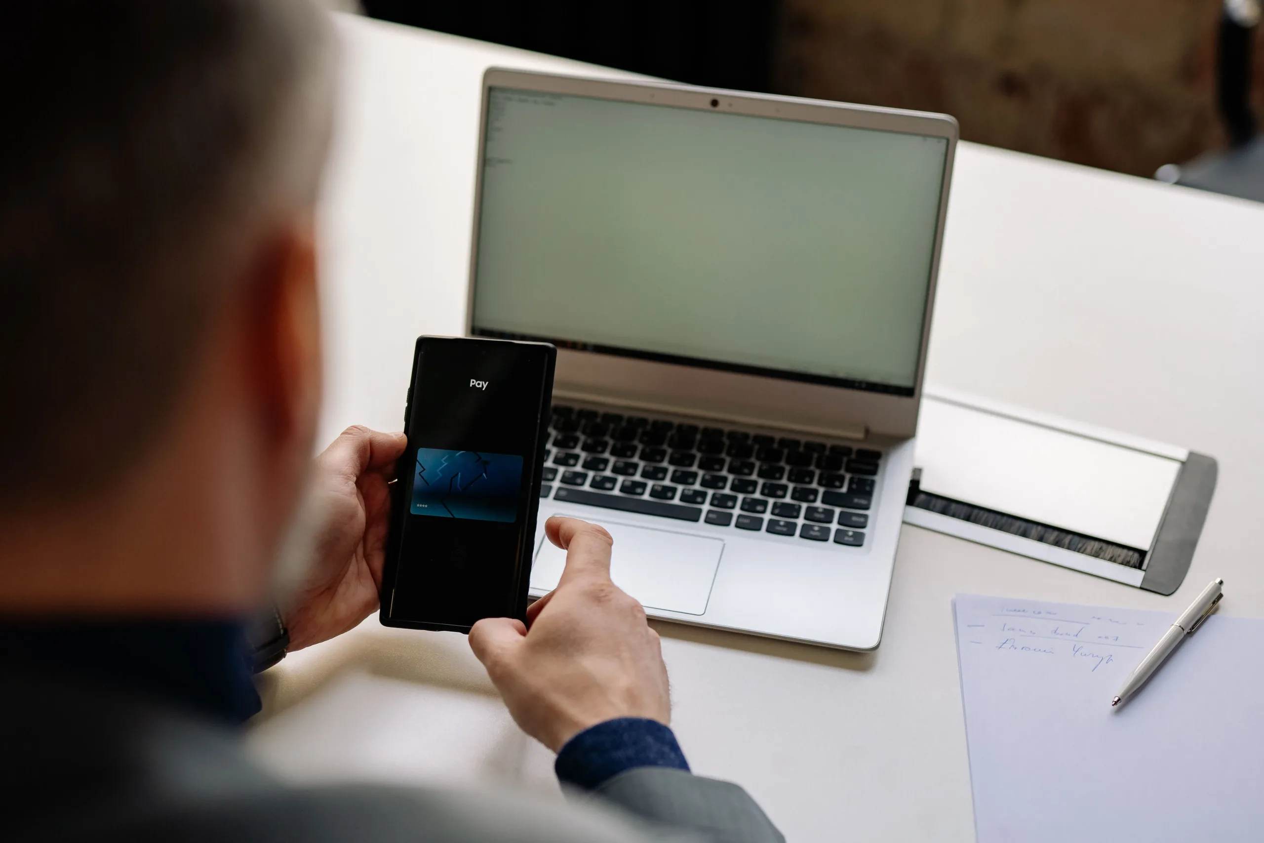 Business director using a mobile banking app and laptop to settle remaining company funds