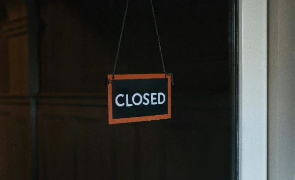 A black and orange closed sign hanging on an office door, illustrating business shutdown during a Creditors Voluntary Liquidation in Singapore.